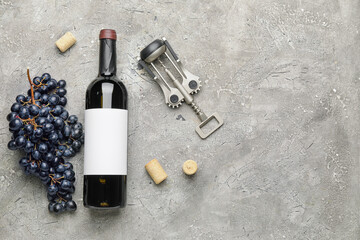 Bottle of red wine with fresh grapes and corkscrew on grunge background