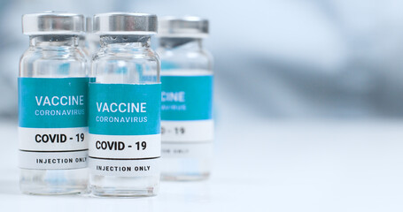 Coronavirus COVID-19 Vaccine Vials. Covid-19 vaccination of the population. SARS-CoV-2 vaccine bottle glass and syringe on a white laboratory table with copyspace.