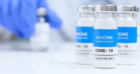 Corona virus Vaccine concept. Female doctor hands in blue medical gloves with transparent liquid coronavirus vaccine bottle and syringe for injection in the laboratory. Research and development of new