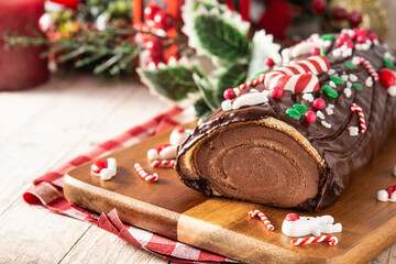 Chocolate yule log christmas cake on wooden table	
