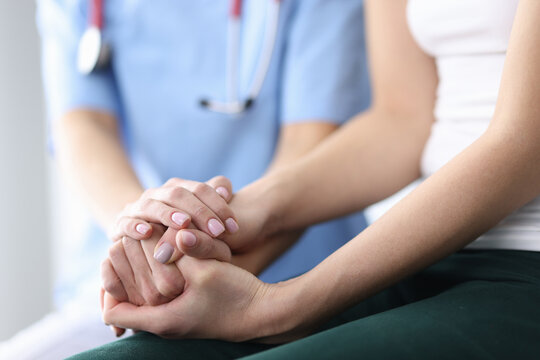 Patient's and doctor's hands are folded together. Medical care and support concept