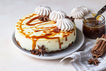 Vanilla cheesecake with carrot cake crust served with salty caramel topping and meringue, light concrete background. Selective focus.