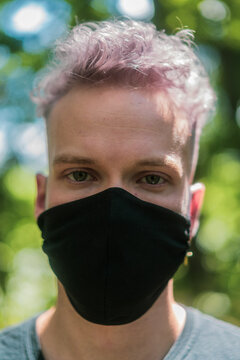 portrait of young man wearing a black face mask outdoors during pandemic