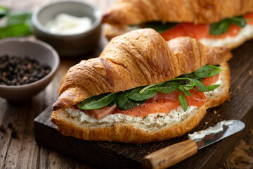 croissant with salmon, spinach and cream cheese on a wooden board, selective focus, close-up