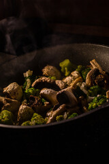 White champignons, onion and green broccoli fry on pan or wok. Hot delicious vegetarian dinner.