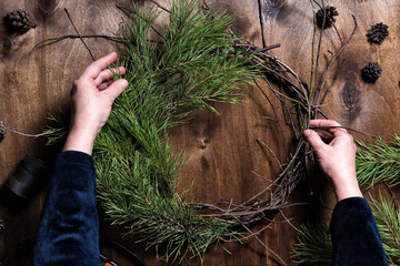 Woman making christmas wreath from nature branches.