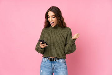Young woman over isolated pink background surprised and sending a message