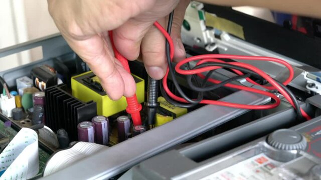 Technician using multi meter to check electronic board of an electrical equipment.