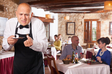 Fototapeta na wymiar Male waiter demonstrating his upset with little tips from restaurant visitors