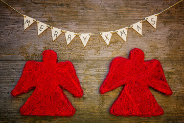 Christmas or New Year decoration background with two red angels under a sling with Merry Xmas on a...