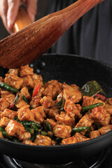 Making/Sauteeing  Orek Tempe, Indonesian Cuisine Made from Cubed Tempeh with Spice, Chilli, and Sweet Soy Sauce. Using Wooden Spatula, Home Cooking Process in the Kitchen