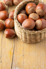 Aerial view of hazelnuts in basket on rustic table, with selective focus, vertical, with copy space