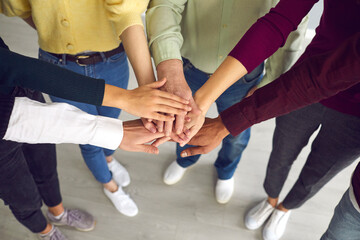 Close-up of business people or friends putting hands together as symbol of cooperation, teamwotk, unity