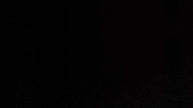 White spray on a dark background splashes on the left. Sneezing air drip particles, close-up.