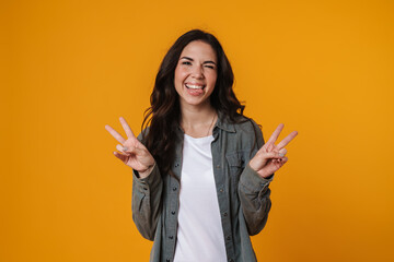 Cheerful beautiful girl gesturing peace sign and winking at camera