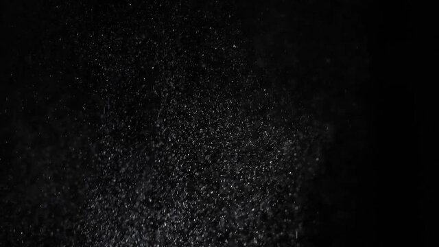 White spray on a dark background splashes on different sides. Sneezing air drip particles in slow motion, close-up.