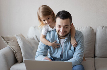 Work from home. Man working on laptop with child playing around. businessman watching child and spending time with kid. Freelance concept. Happy modern family.