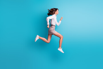 Fototapeta na wymiar Full size profile photo of brunette girl jump run wear shirt skirt sneakers isolated on teal background