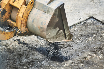tractor unloading hot asphalt into the pit. road repair