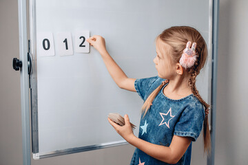 Portrait of cute smart intelligent kid arranging numbers in the correct order. Beautiful child holding a card with number 2. Concept of mathematics. photo with noise.