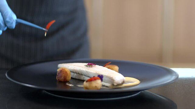 Hands of a hotels  restaurant chef putting the finishing touches on his fish dish