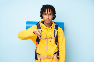 Young mountaineer african american man with a big backpack isolated on a blue background showing thumb down sign