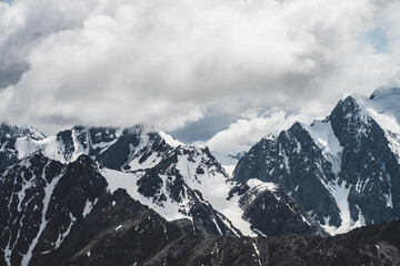 Atmospheric minimalist alpine landscape with massive hanging glacier on big mountain under cloudy...