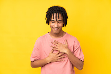 Young african american man isolated on yellow background smiling a lot