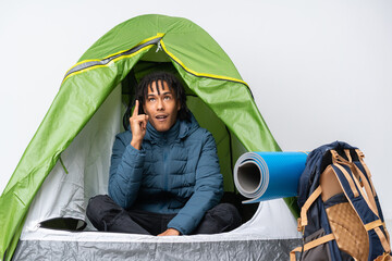 Young african american man inside a camping green tent thinking an idea pointing the finger up