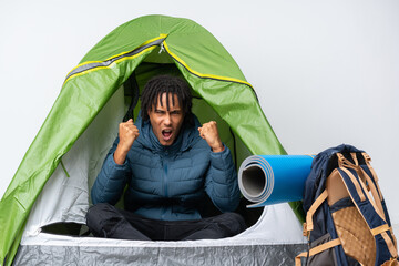Young african american man inside a camping green tent frustrated by a bad situation