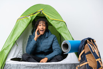 Young african american man inside a camping green tent with surprise and shocked facial expression