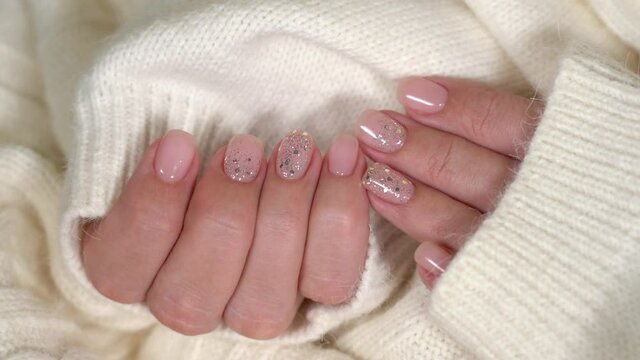Closeup view 4k video of beautiful manicured female hands isolated on fluffy soft white texture of cozy sweater.