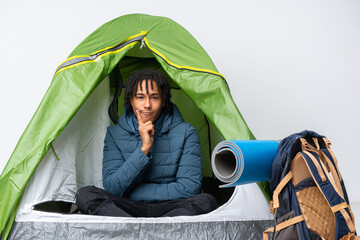 Young african american man inside a camping green tent and looking front