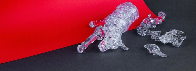 Broken figurine of a bull from three dimensional puzzles on red and gray background. Symbol of coming New Year 2021, business, stock exchange, finance, difficulties. Banner.