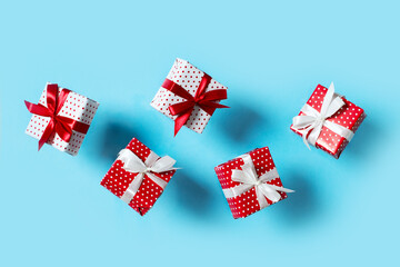 Fototapeta premium Polka dot pattern red gift box with ribbon and falling on blue background