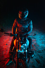 biker with black helmet sitting on his bike at night and colorful lights	

