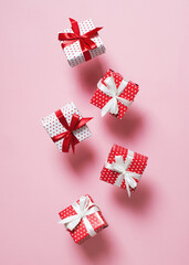 Polka dot pattern red gift box with ribbon falling on pink background