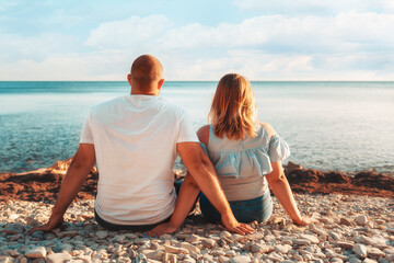 An adult couple, a plus-size man and woman, sit on the beach, admiring the ocean. Rear view. The concept of Valentine's day