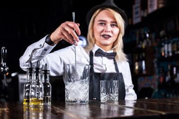 Confident woman bartending adds ingredients to a cocktail at the nightclub