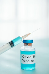Glass vial with vaccine against covid-19 vaccine and syringe on table in laboratory