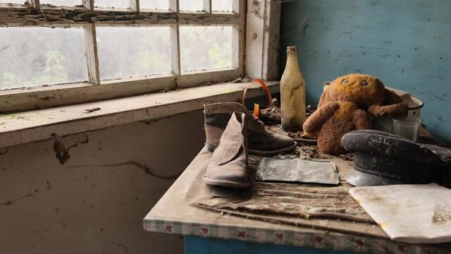Chernobyl zone, Ukraine. Visit to Pripyat Ghost Town - 4K. table, boots, soft toy cheburashka, hat are on the table by the old window 2020