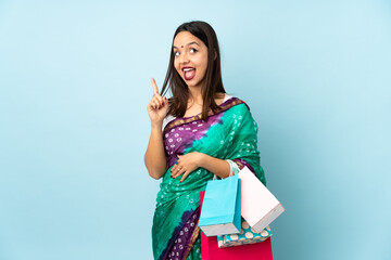 Young Indian woman with shopping bags intending to realizes the solution while lifting a finger up