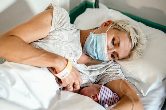 A new mother nursing her newborn boy in mask during pandemic
