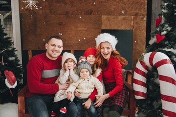 Two sisters and brother hug near the Christmas tree. Waiting for Santa Claus. open gifts. Big...