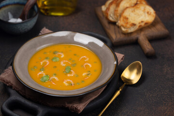 Pumpkin soup with shrimps and basil oil with toasted bread. Copy space.