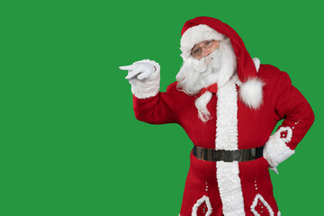 santa claus on a green background stands points with two fingers at an empty space for the text. Copy space.
