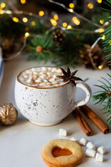A cup of hot chocolate with marshmallows and linzer cookie on a light background.