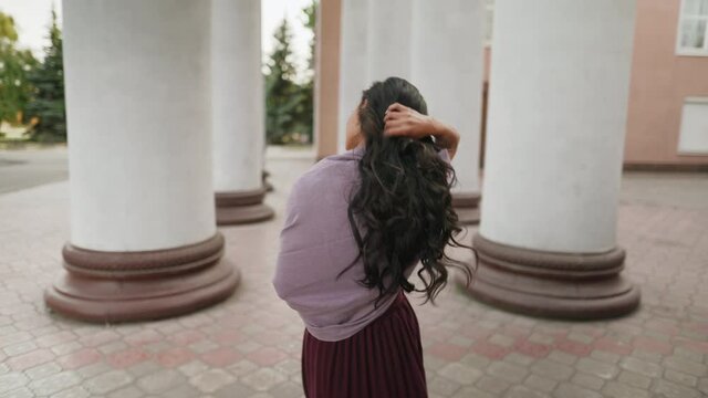 Back view of young pretty wonan walking along the columns