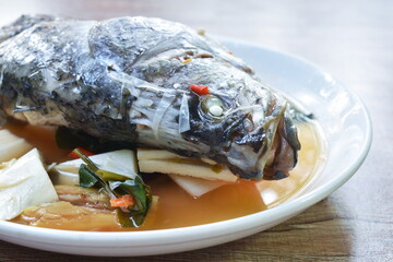 spicy bass fish head and slice coconut shoot in Tom Yum soup on plate