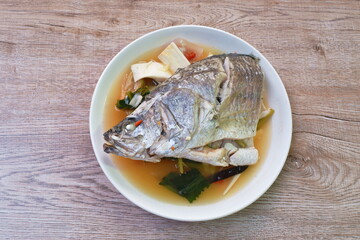 spicy bass fish head and slice coconut shoot in Tom Yum soup on plate